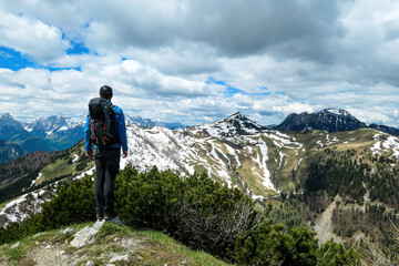 Fototapeta premium Hiker man breathing on the summit of Hahnkogel (Klek) with scenic view on mountain peaks in the Karawanks and Julian Alps, Carinthia, Austria. Border with Slovenia. Triglav National Park. Freedom
