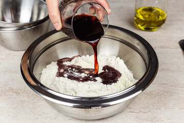 Woman's hands pouring red wine in a bowl with flour to prepare a recipe