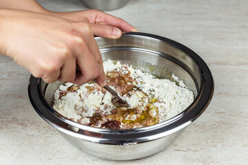 Women's hands blend in a steel bowl the ingredients for home taralli preparation
