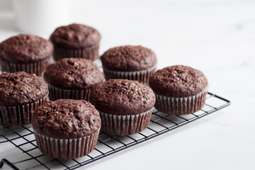 Freshly baked chocolate muffins on a grid on white table