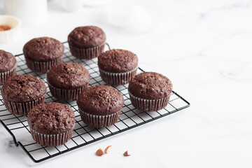 Freshly baked chocolate muffins on a grid on white table