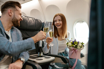 Cheerful couple toasting with champagne in airplane