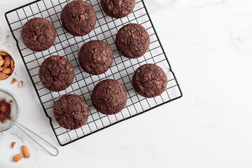 Freshly baked chocolate muffins on a grid on white table