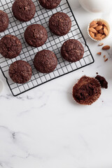 Freshly baked chocolate muffins on a grid on white table