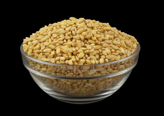 Wheat grains in glass bowl isolated on black background