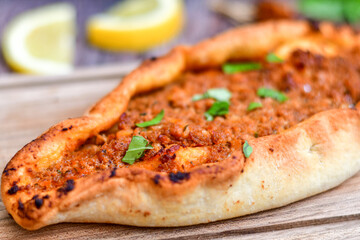  Traditional Turkish cuisine. Baked Pide dish with minced  beef, tomatoes and  herbs on  wooden background.  Turkish pizza pide