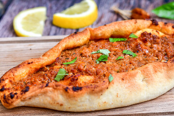 Traditional Turkish cuisine. Baked Pide dish with minced  beef, tomatoes and  herbs on  wooden background.  Turkish pizza pide