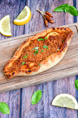  Traditional Turkish cuisine. Baked Pide dish with minced  beef, tomatoes and  herbs on  wooden background.  Turkish pizza pide