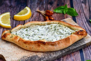  Traditional Turkish cuisine. Baked Pide dish with  cheese and  herbs on  wooden background.  Turkish pizza pide
