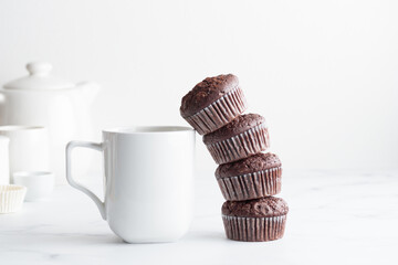 The stack of chocolate muffins with a white mug