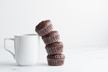 The stack of chocolate muffins with a white mug