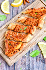  Traditional Turkish cuisine. Baked Pide dish with minced  beef, tomatoes and  herbs on  wooden background.  Turkish pizza pide