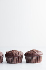 The row of chocolate muffins on a white table