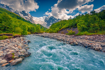 Blue water of Adishchala river. Majestic morning view of Shkhara Mountain in Caucasus mountains....