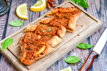  Traditional Turkish cuisine. Baked Pide dish with minced  beef, tomatoes and  herbs on  wooden background.  Turkish pizza pide
