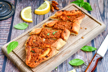  Traditional Turkish cuisine. Baked Pide dish with minced  beef, tomatoes and  herbs on  wooden background.  Turkish pizza pide
