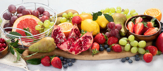 Assortment of colorful ripe tropical fruits on light gray background.