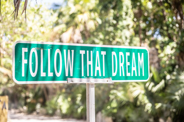 Motivational quote saying Follow That Dream on a sign next to a road in the nature