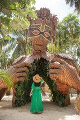 Giant sculpture by Daniel Popper called Ven a la Luz, or Coming into Light, in Tulum, Mexico, with a woman in green dress standing in front of it - obrazy, fototapety, plakaty