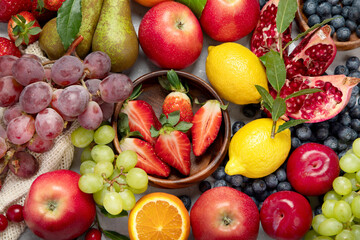 Assortment of colorful ripe tropical fruits on light gray background.