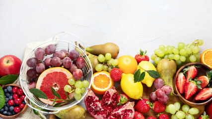 Assortment of colorful ripe tropical fruits on light gray background.