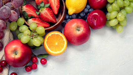Assortment of colorful ripe tropical fruits on light gray background.