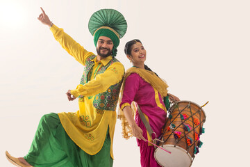 Sikh couple performing bhangra and playing drum during Baisakhi celebration