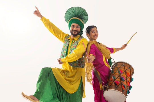 Sikh couple performing bhangra and playing drum during Baisakhi celebration