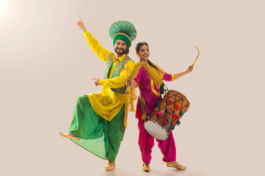 Sikh couple performing bhangra and playing drum during Baisakhi celebration