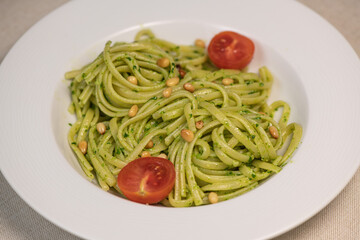 green spinach spaghetti with cheese and tomato on wooden table. High quality photo