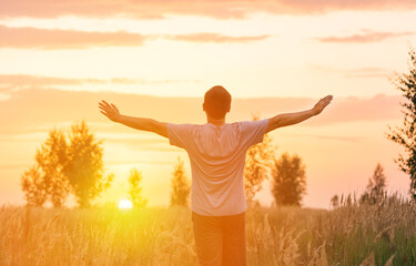 Freedom. A man looks at the setting sun with his arms outstretched