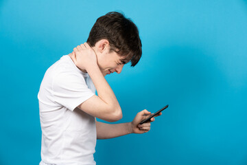 Teenager boy using phone with neck pain. Bad posture and digital addiction on puberty concept