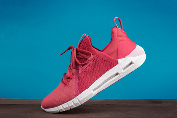 Running sports shoe on blue background. Running shoe, sneaker or trainer. Women's athletic shoe....