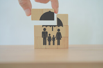 hand complete  umbrella over family icon on wooden cube blocks, for life or group insurance