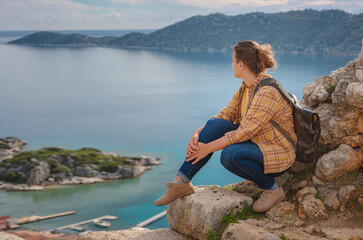 Fototapeta premium Travel and tourist attractions at Kekova island, Turkey. Woman traveler explores ruins castle of Simena with view of sea bay and Kekova Island with famous flooded city. Tourist attractions in Turkey.