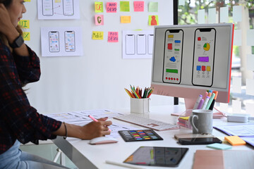 Young female website designer working in a studio to create application for mobile phone.