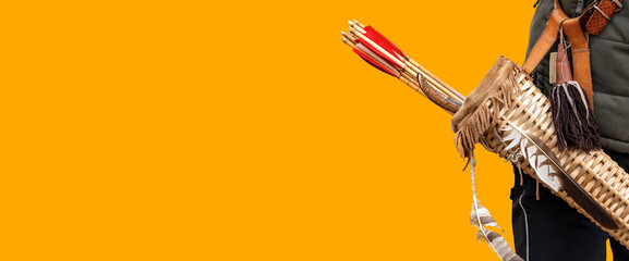Close-up of an archer with a vintage quiver and wooden arrows isolated on orange background with...