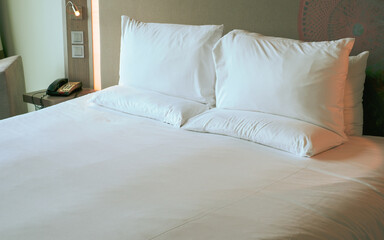 Clean Bedding sheets and pillow on natural wall room background. White bedding and pillow in hotel...