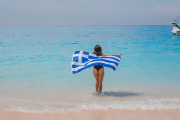 happy sexy woman running by sea beach with greece flag