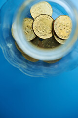 top view of saving jar with coins against blue background