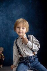 Cute portirait of blond preschool child, boy, on blue background