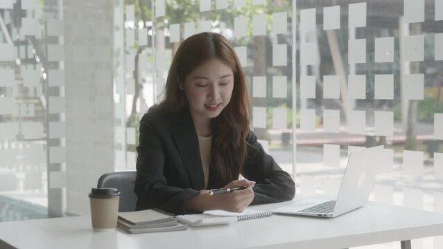 Young beautiful business woman is calculating and working on laptop then writing on note books. 