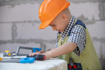 Child in helmet is construction worker. Foreman kid work in the hard hat making repairs. Childhood...