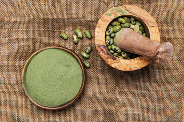 supergreens powder and green beans in a burlap mortar and whisk.  Healthy food concept.
