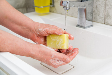 Closeup of a woman washing her hands in bathroom to prevent l infection