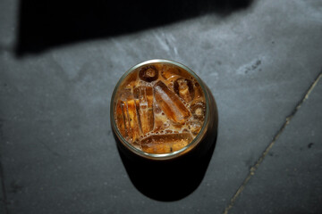 Ice coffee on table with cream being poured into it showing the texture and refreshing look of the drink