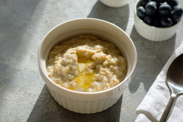 oatmeal porridge with blueberries and butter on grey background. Healthy eating, dieting, fitness food lifestyle concept