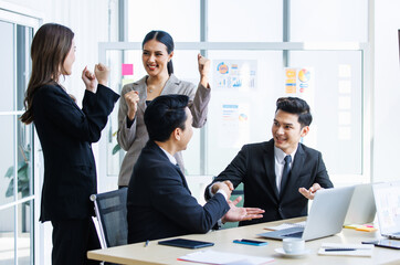 Group of Asian young happy male and female professional successful businessman businesswoman employee colleagues in formal suit celebrating job achievement holding fists up shaking hands together