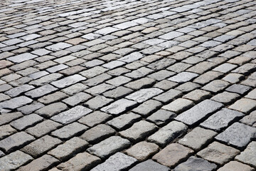 Stone pavement texture, cobbled street in sunlight. Old paved road with tiles from cobblestones