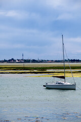 view from the beach of la patache on the preparing of  a boat for sailing with the church of Ars-En-Re in the background on the isle of ile de Re in France
